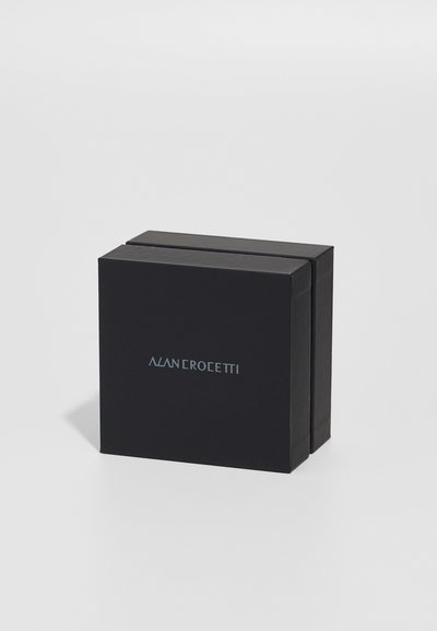 Schwarze Pappbox in quadratischer Form, mit einem hellblauen Logo "ALAN CROCEITTI" auf der Vorderseite und einer matten Oberflächenstruktur.