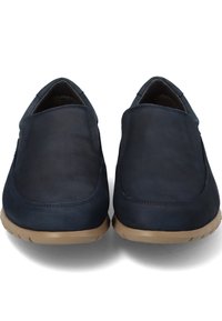 Zapatos de cuero azul marino tipo slip-on con una textura suave, punteras redondeadas y suelas de goma color marrón claro. Costuras mínimas y sin hardware visible.