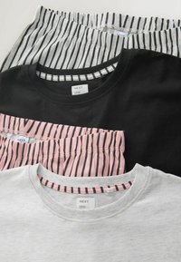 Tre t-shirts: en sort bomulds crew neck, en lys grå t-shirt og en lyserød stribet design. Etiketterne viser mærket "NEXT."