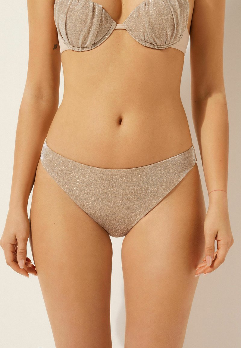 Bikini-set med guldglimmer som har en vadderad bh med mjuka kupor och matchande högmidjade trosor, som visar en slät yta och elegant design.