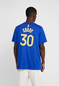 Modré bavlněné tričko s kulatým výstřihem, na zádech s nápisem "CURRY" a číslem "30" tučně žlutě, s logem NBA u výstřihu.