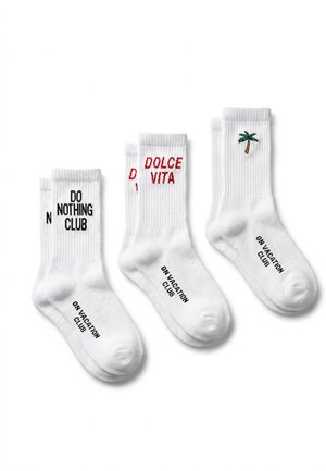 Trois paires de chaussettes blanches à tige moyenne affichent les inscriptions « Do Nothing Club » et « Dolce Vita », ainsi qu’un palmier ; toutes portent le texte « On Vacation Club » sur le pied.