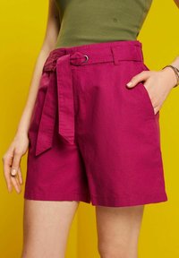 Pantalones cortos fucsias con cintura ancha, bolsillos frontales y detalle de cinturón atado, hechos de una tela suave y ligera.