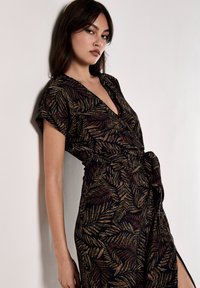 Robe noire à manches courtes avec un motif de fougère dans des tons dorés et rouges, décolleté en V plongeant et détail de taille nouée.