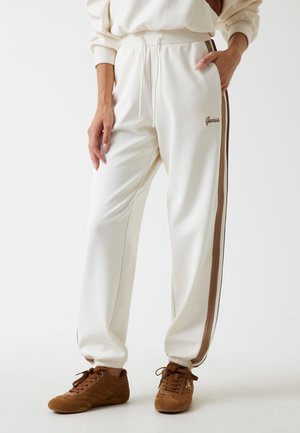 Pantaloni jogger bianchi con strisce laterali marroni, dotati di vita elastica e cordoncino regolabile. Include il logo del marchio sull'anca.
