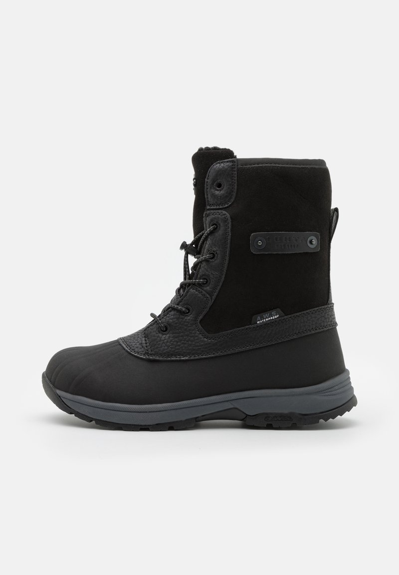 Zwarte waterdichte laars met een rubberen zool, suede bovenkant en leren accenten met textuur. Voorzien van een vetersluiting en een verstevigde teen.