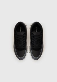 Een paar zwart en grijs veter Sneakers met witte zolen, gezien van bovenaf, gepresenteerd op een eenvoudige witte achtergrond.