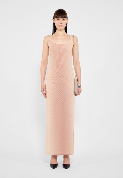 Robe maxi sans manches de couleur rose pâle avec une coupe droite et des bretelles délicates. Tissu lisse et léger avec une texture subtile ; associée à des talons noirs.