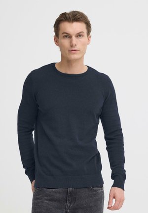 Maglione girocollo blu navy con maniche lunghe, realizzato in tessuto a maglia liscia. Vita e polsini delle maniche a costine per una texture definita.