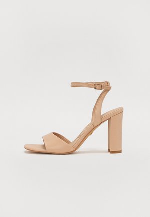 Sandale à talons hauts beige avec bout ouvert, bride avant unique, bride de cheville avec boucle et épais talon bloc sur fond neutre.