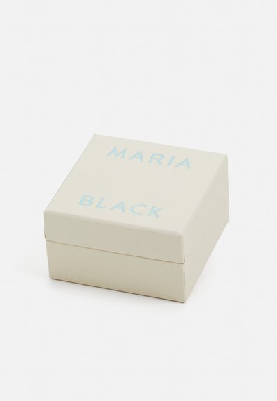 Crème kleurige doos met een gladde textuur, met de tekst "MARIA BLACK" in lichtblauw op het deksel. Vierkante, gesloten vorm.