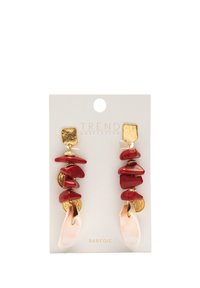 Czerwone, warstwowe kolczyki z złotymi akcentami, o nieregularnych kształtach i gładkim różowym detalem z muszli na dole, zamocowane na karcie.