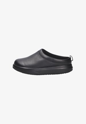 Schwarze Slipper mit einem strukturierten Leder-Obermaterial, runder Spitze und einer dicken Gummisohle. Verfügt über eine hintere Zuglasche für einfaches Anziehen.