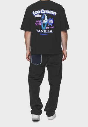 Sort bomulds t-shirt med farverig grafisk tekst på ryggen, der viser et isvaffel med "Is" og "Vanilje" i fede bogstaver.