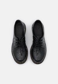 Chaussures noires en cuir à lacets avec un motif texturé, un bout rond et une couture jaune le long de la semelle, dotées d'une semelle intérieure rembourrée pour le confort.