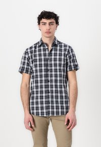 Kratka majica s dugim rukavima s gumbima u tamnoplavoj, crnoj i bijeloj tartan uzorku. Ima klasičan ovratnik i glatku, laganu tkaninu.