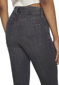 Jean en denim noir avec une patch arrière, arborant un logo classique de Levi Strauss, deux poches arrière et une silhouette ajustée.