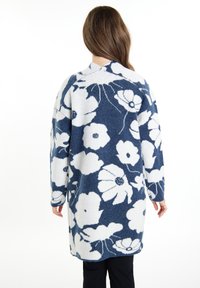 Cardigan lungo con motivo floreale nei colori blu navy e bianco, dal tessuto morbido e con vestibilità over-size. Scollo a V sul retro, maniche lunghe.