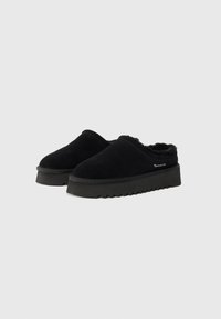 Pantofi slip-on negri din suede, cu o căptușeală pufoasă, talpă groasă din cauciuc negru cu un model în zigzag și branding discret pe lateral.
