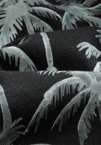 Black fabric with a textured weave, featuring a gray palm leaf pattern. The design is repetitive with varying leaf shapes and sizes.