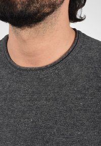 Suéter gris de punto con cuello redondo, tejido texturizado y una vista cercana del cuello y la zona del collar.