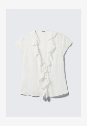 Valkoinen pellavapusero, jossa on röyhelökaulus ja -edusta, lyhyet hihat ja solmittava vyötärötaiote. Kevyt ja teksturoitu viimeistely.