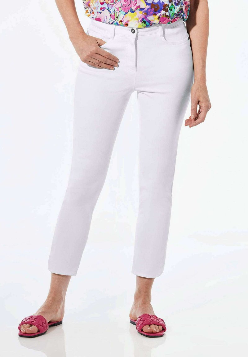 Weiße Jeans mit einer taillierten Passform und Fünf-Taschen-Stil, ausgestattet mit einem Reißverschluss und einem einzelnen Knopfverschluss. Kombiniert mit geflochtenen rosa Slides.