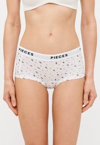 Cuecas hipster brancas de algodão com uma cintura preta "PIECES", apresentando um padrão floral de pequenas folhas e botões. Tecido macio e elástico.