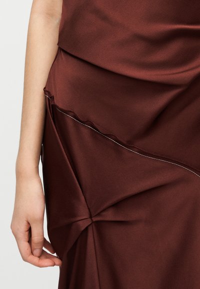 Μπορντό φόρεμα από απαλό ύφασμα, με ρυθμισμένες λεπτομέρειες και αντίθετη λευκή ραφή κατά μήκος των ραφών.