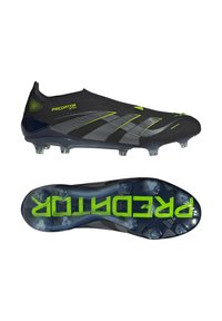 Black soccer cleats with a textured surface, featuring reflective silver stripes and neon green accents. Transparent cleats with a patterned sole.
