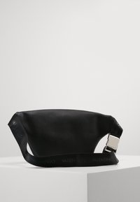 Svart läderväska med en rundad form, med en strukturerad yta, en bred axelrem med "Valentino"-logotyp och en metallisk spänne.