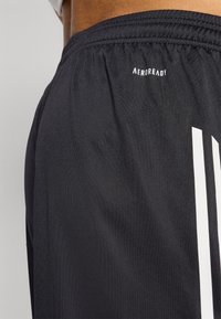 Zwarte sportshorts van gladde stof, met een elastische tailleband en witte strepen aan de zijkant. Het "AEROREADY" logo is zichtbaar.
