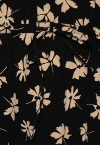 Tessuto nero con motivo floreale beige. Superficie texturizzata con un dettaglio a cintura legata in vita. Accentuato da grandi foglie stilizzate.