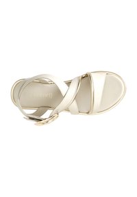 Cream-colored strappy sandal with a smooth texture, featuring crossed straps and a gold-tone metal buckle accent. Modern flat sole design.