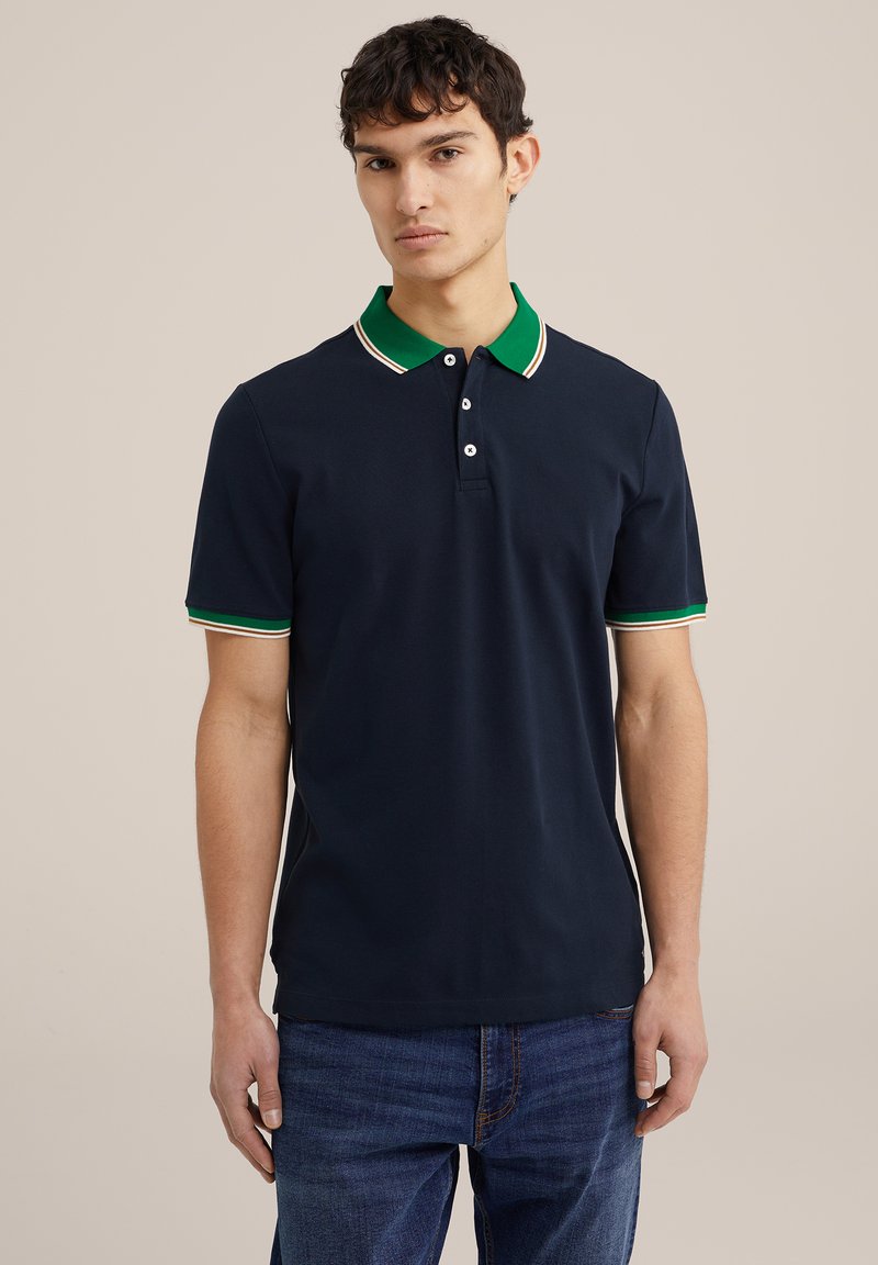 Polo marine avec col vert, arborant des accents rayés blancs et rouges sur les manches et une patte de boutonnage à trois boutons. Design décontracté en coton.
