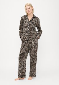Pysjamasett med leopardmønster i et mykt stoff, som har en skjorte med knapper og krage samt løstsittende bukser med sidelommer.
