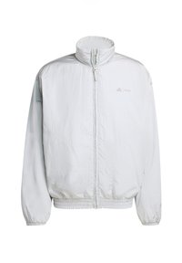 Chaqueta blanca ligera con un collar alto, cremallera frontal y puños elásticos. Presenta una textura sutil y una marca en el área del pecho izquierdo.