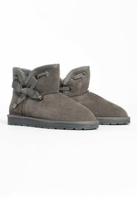 Botines de ante gris con un forro interior suave, que cuentan con una cinta envolvente y acentos decorativos de hardware en el costado. Suelas de goma planas.