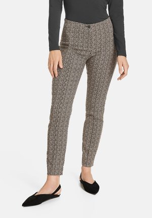 Vzorované kalhoty v béžových a hnědých tónech, se štíhlým střihem a délka ke kotníkům. Materiál má geometrický vzor ve tvaru diamantů.