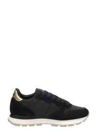 Zapatilla negra que combina materiales de ante y sintéticos, con una suela blanca y un detalle dorado en el talón. Diseño con cordones.