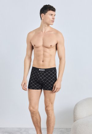 Schwarze Boxershorts mit Diamantmuster und einem Bund mit Logo. Das Material ist glatt und enganliegend und bietet ein modernes Design.