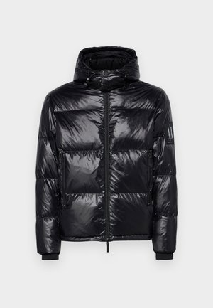 Black puffer jacket with a shiny, quilted texture, detachable hood, zip front, and zippered pockets. Features a logo on the sleeve.