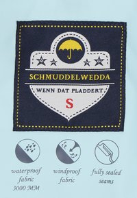 Tamsus audinys su balta ir geltona siuvinėjimu; vaizduoja skėtį, žvaigždes, tekstą "SCHMUDDELWEDDA" ir ikonas, nurodančias vandeniui atsparumą, vėjui atsparumą ir sandarias siūles.