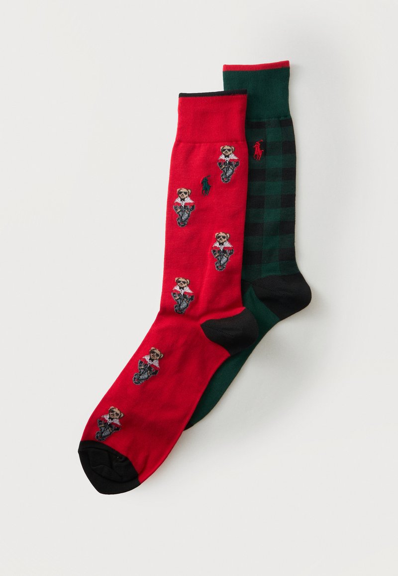 Une chaussette rouge avec de petites figures de chiens portant des vestes et une chaussette à carreaux noire et verte avec un logo cheval rouge.