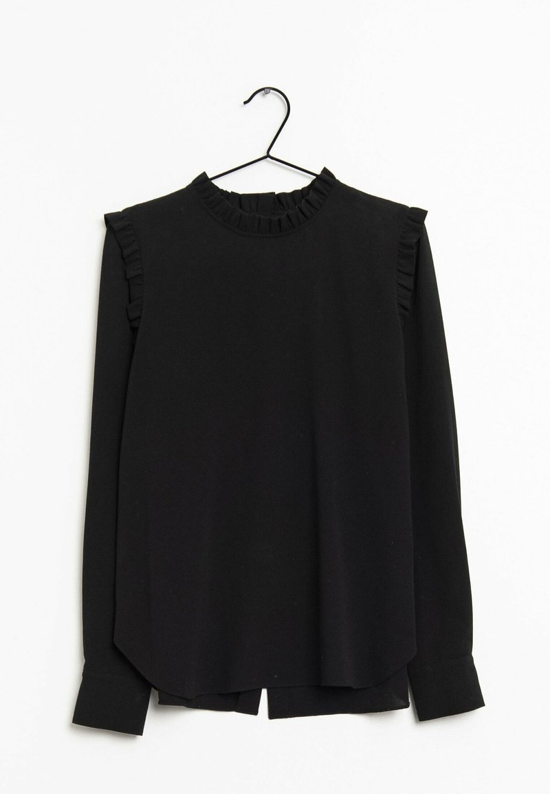 Blouse noire à manches longues avec poignets, épaules et encolure volantés accrochée à un cintre sur fond blanc.