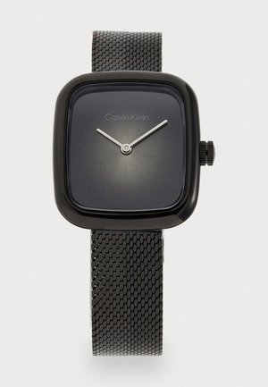 Montre carrée pour homme avec un bracelet en maille métallique noir mat. Le cadran sombre présente des aiguilles argentées et un logo de marque discret en haut.
