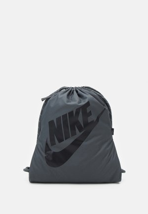 Donkergrijze Nike rugzak met trekkoord, voorzien van een zwart logo en sluiting met trekkoord, afgebeeld tegen een witte achtergrond.