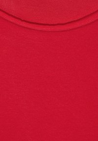 Tessuto di cotone rosso con una trama liscia, con scollo rotondo nella parte superiore e superficie uniforme e costante in tutta la lunghezza.