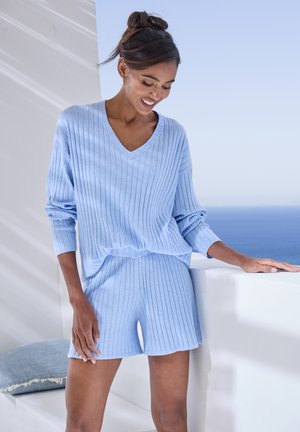 Light blue knitted loungewear set featuring a V-neck oversized top with ribbing and matching shorts. Soft texture, casual fit.