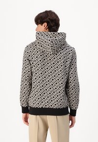 Black and white patterned hoodie with a textured geometric design, featuring a drawstring hood and black ribbed cuffs and hem.
